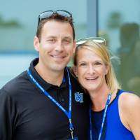 Two people posing in front of the new Jamie Hosford Football Center.